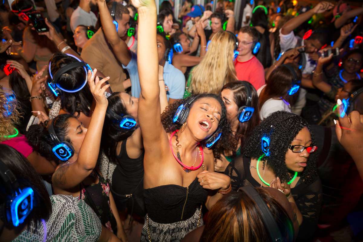 Young people wearing silent disco headphones in a nightclub